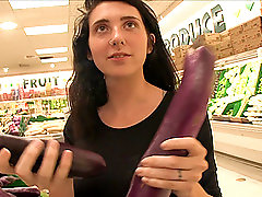 Darh haired Lexi has fun with vegetables in a public store
